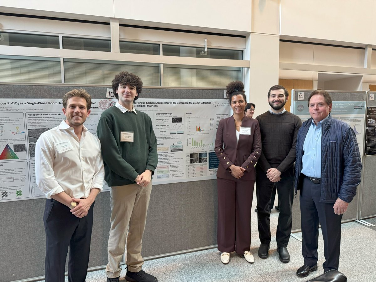 The Quantera team standing in front of scientific posters.