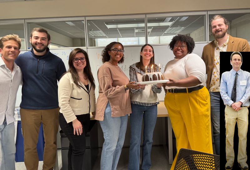 Researchers gathered in an office, one holding a cake.