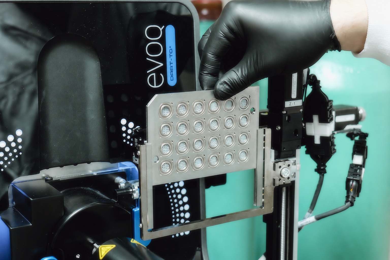 A gloved hand holding the loaded cartridge array at a DART-MS instrument ready for analysis
